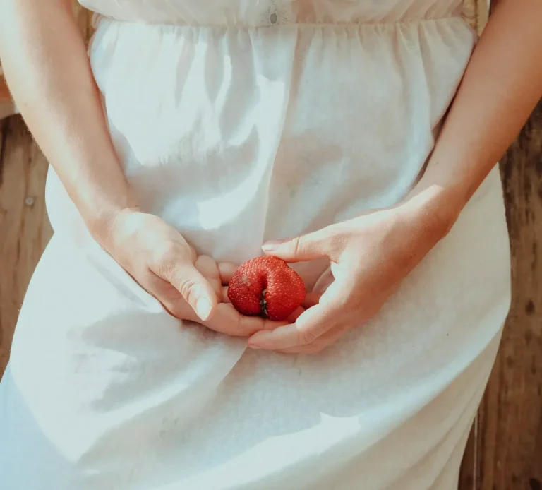 Donna vestita di bianco che tiene in mano una fragola